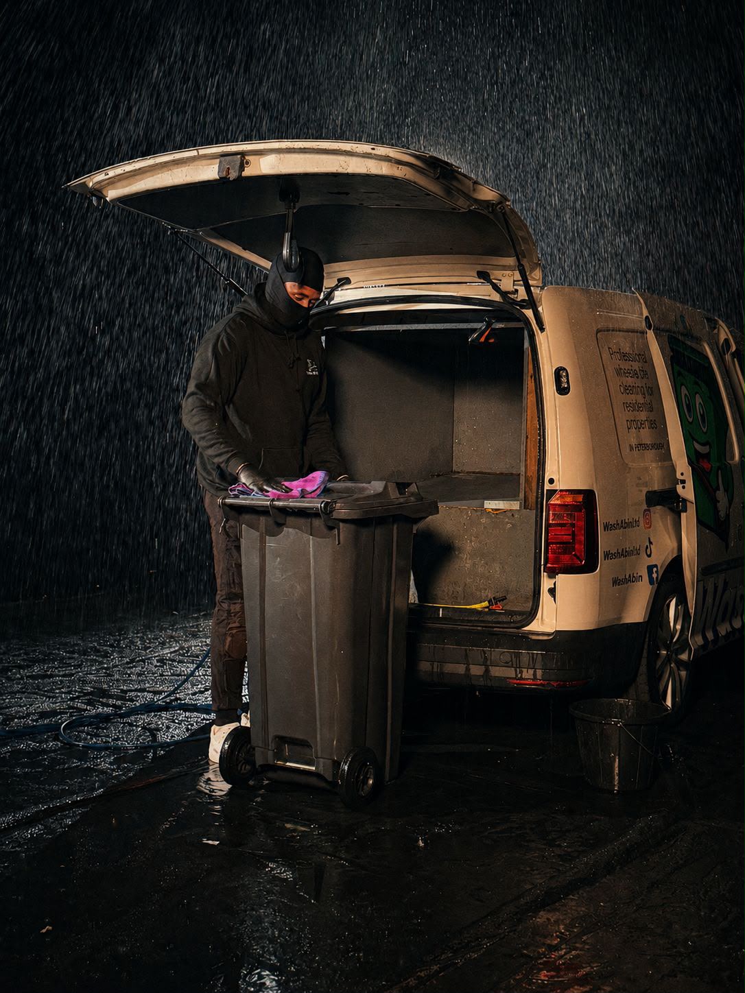 Wash A Bin team cleaning bins in the rain next to the branded van