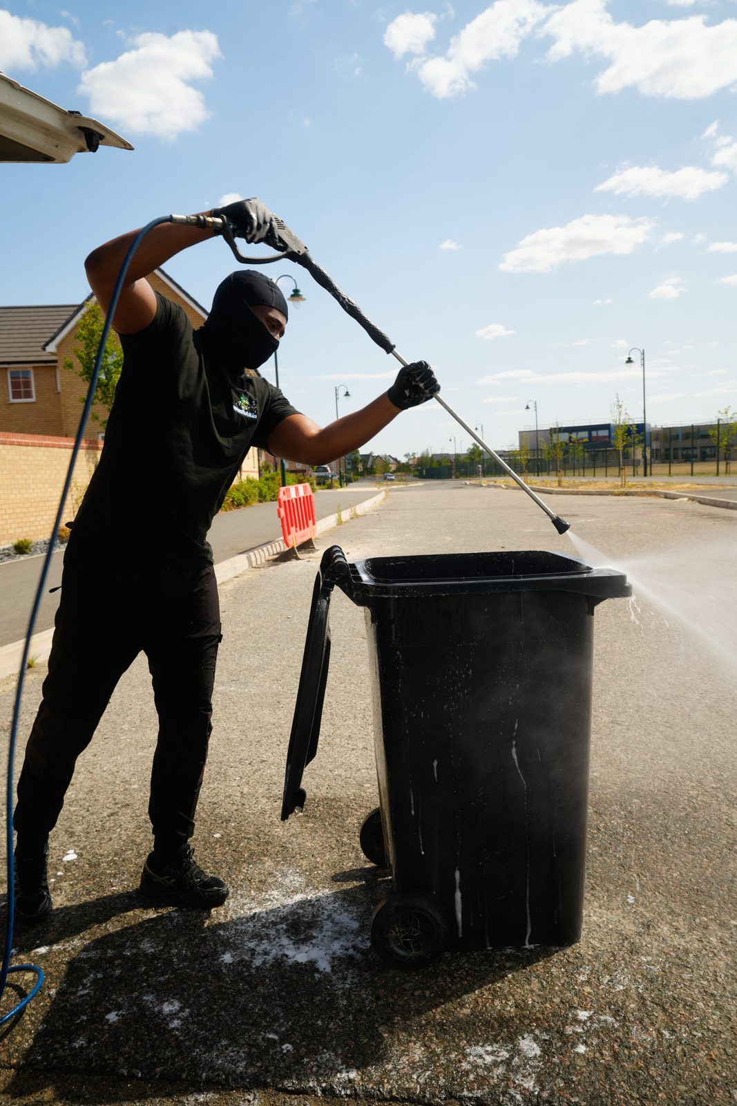 Jet-washing a black wheelie bin